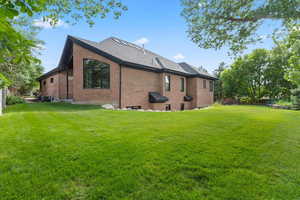 View of side of property featuring brick siding, a lawn, and a shingled roof
