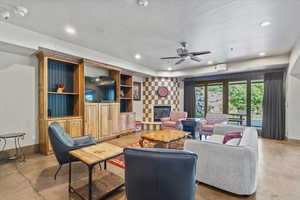 Living room with recessed lighting, concrete floors, a stone fireplace, and ceiling fan