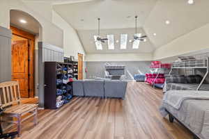 Bedroom featuring light wood-style flooring, a skylight, high vaulted ceiling, arched walkways, and recessed lighting