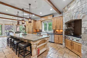 Kitchen with stainless steel appliances, beamed ceiling, stone tile floors, recessed lighting, and decorative backsplash