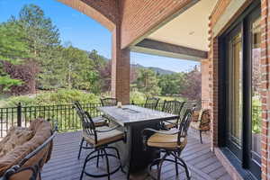 Wooden terrace featuring outdoor dining space and view of scattered trees