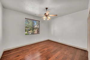 Unfurnished room featuring dark wood-style flooring and ceiling fan