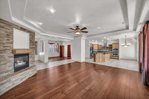 Unfurnished living room featuring a raised ceiling, a fireplace, a chandelier, light wood-style flooring, and a textured ceiling