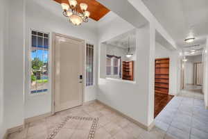 Tiled foyer entrance featuring baseboards and a chandelier
