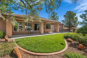 Rear view of property with stucco siding, a patio area, a tile roof, and a lawn