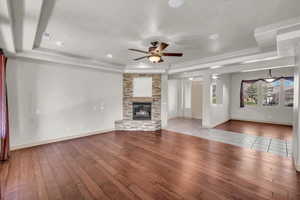 Unfurnished living room with hardwood / wood-style floors, a raised ceiling, ceiling fan, a fireplace, and recessed lighting