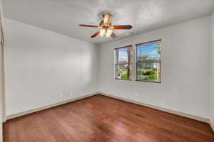 Unfurnished room featuring dark wood-type flooring and a ceiling fan