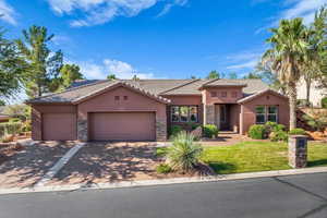 Mediterranean / spanish home featuring stucco siding, stone siding, a garage, a tile roof, and a front lawn