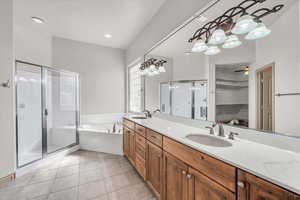 Bathroom featuring a garden tub, a shower stall, double vanity, and tile patterned flooring