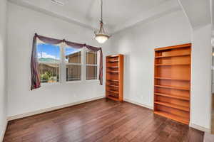 Empty room featuring dark wood-style flooring and baseboards