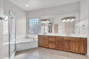 Bathroom featuring a garden tub, double vanity, tile patterned flooring, and a stall shower