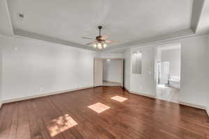 Spare room featuring hardwood / wood-style flooring, a ceiling fan, and a raised ceiling