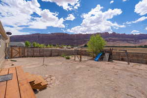 Fenced backyard featuring a playground and a mountain view