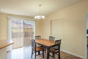 Dining room featuring dark wood-style floors, a chandelier, and vaulted ceiling