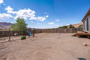 Fenced backyard featuring a playground and a mountain view