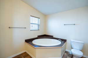 Bathroom featuring a garden tub and lofted ceiling