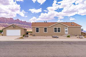 Manufactured / mobile home with a mountain view, an outbuilding, a shingled roof, and concrete driveway