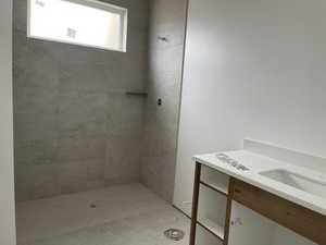 Full bath featuring tiled shower and vanity