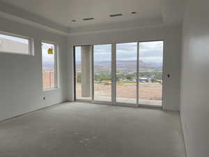 Unfurnished room featuring a tray ceiling, concrete floors, and a mountain view