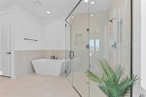 Bathroom featuring a freestanding bath, tile walls, a stall shower, recessed lighting, and tile patterned flooring