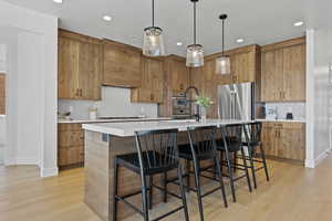 Kitchen with tasteful backsplash, a kitchen island with sink, a breakfast bar, decorative light fixtures, and recessed lighting