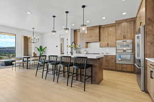 Kitchen with a center island with sink, decorative light fixtures, a kitchen bar, decorative backsplash, and recessed lighting