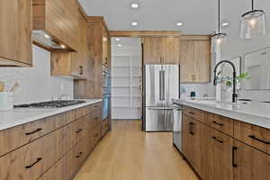 Kitchen with backsplash, light wood-style flooring, stainless steel appliances, decorative light fixtures, and recessed lighting