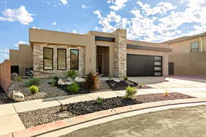 Contemporary house featuring stone siding, stucco siding, driveway, and a garage