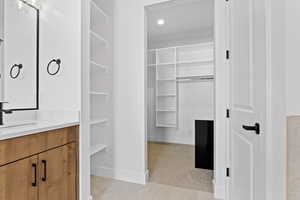Bathroom with vanity, a walk in closet, light tile patterned floors, and recessed lighting