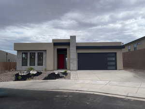 Contemporary home with an attached garage, concrete driveway, and stucco siding