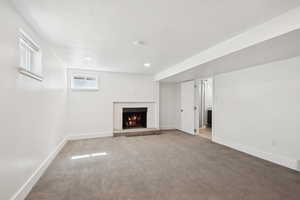 Basement featuring carpet floors, a brick fireplace, a textured ceiling, and recessed lighting
