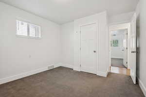 Unfurnished bedroom with dark colored carpet and baseboards