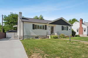 Ranch-style home with concrete driveway, brick siding, a garage, an outbuilding, and a chimney
