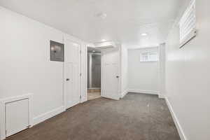 Below grade area with electric panel, carpet flooring, a textured ceiling, and recessed lighting