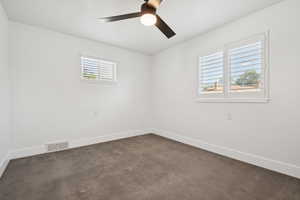 Unfurnished room featuring ceiling fan and dark colored carpet