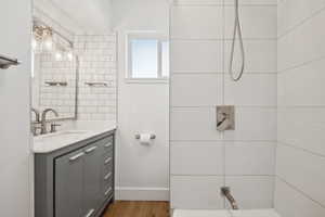 Full bath featuring vanity, tiled shower, and wood finished floors