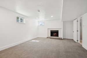 Unfurnished living room with a brick fireplace, carpet floors, a textured ceiling, and recessed lighting