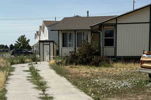 View of front facade with a shingled roof, a shed, and driveway