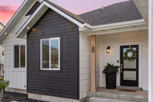 Exterior entry at dusk with a shingled roof