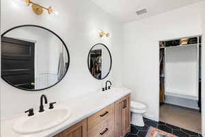 Primary bathroom featuring double vanity, a spacious closet, and tile patterned floors