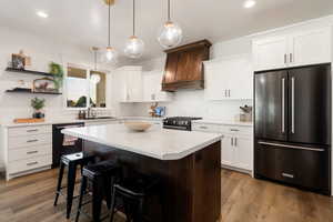 Kitchen featuring high end fridge, dishwasher, range with gas stovetop, light countertops, and a breakfast bar area