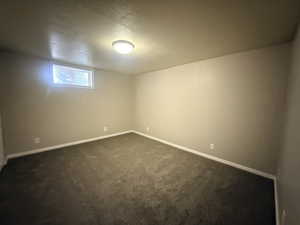 Spare room with a textured ceiling and dark colored carpet