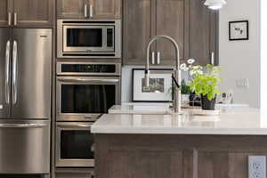 Kitchen featuring appliances with stainless steel finishes, dark brown cabinetry, and light countertops