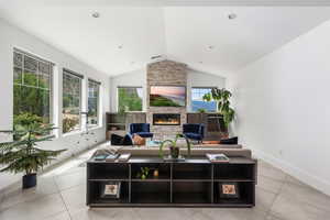 Living room featuring lofted ceiling, a fireplace, and light tile patterned floors