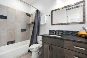 Full bath featuring vanity, shower / tub combo with curtain, and backsplash