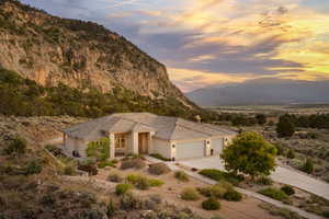 View of front of house with driveway, a mountain view, a garage, stucco siding, and a tiled roof