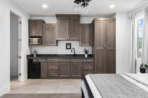 Kitchen featuring stainless steel microwave, dark countertops, recessed lighting, light tile patterned flooring, and dark brown cabinetry
