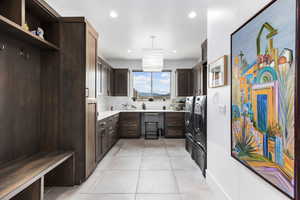 Kitchen with independent washer and dryer, dark brown cabinetry, light tile patterned floors, open shelves, and light countertops