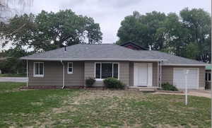 Ranch-style home featuring a garage, a front yard, and driveway