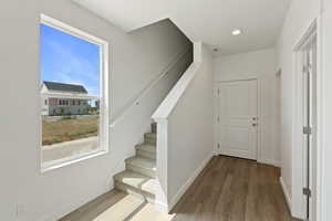 Stairs featuring wood finished floors and recessed lighting
